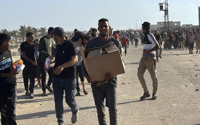 Grupos de palestinos recogen paquetes de ayuda humanitaria en uno de los puestos de la polémica Fundación Humanitaria para Gaza.