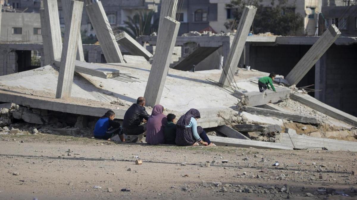 Una familia de palestinos se sienta ante los restos de una casa destruida en el campamento de refugiados de Al Nuseirat.