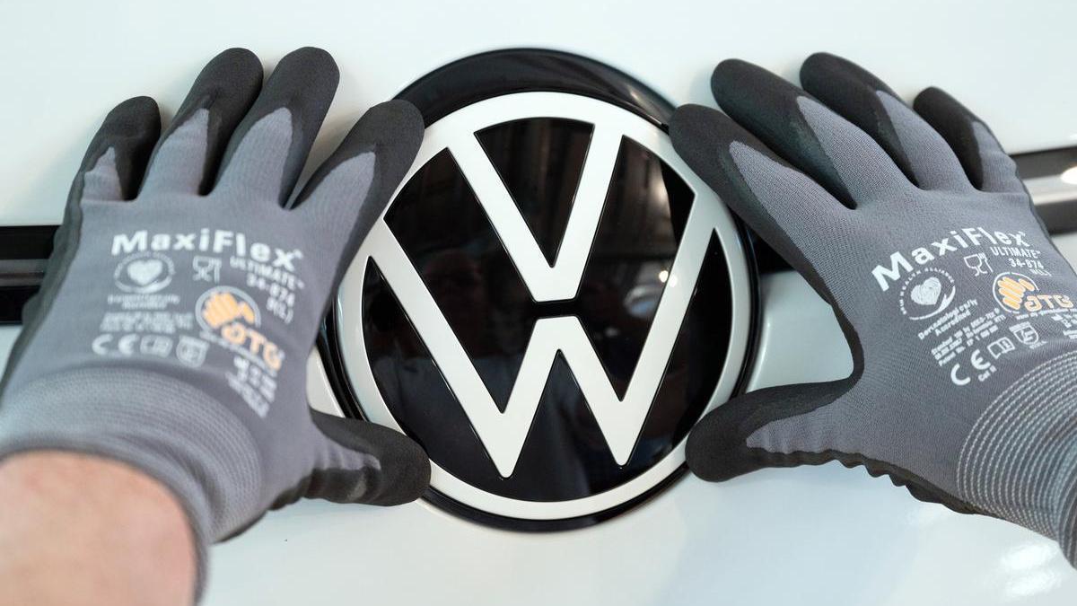 Un trabajador coloca el logo de Volkswagen en un vehículo de la compañía alemana.