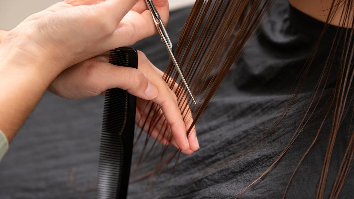Una estilista corta el pelo a una clienta.
