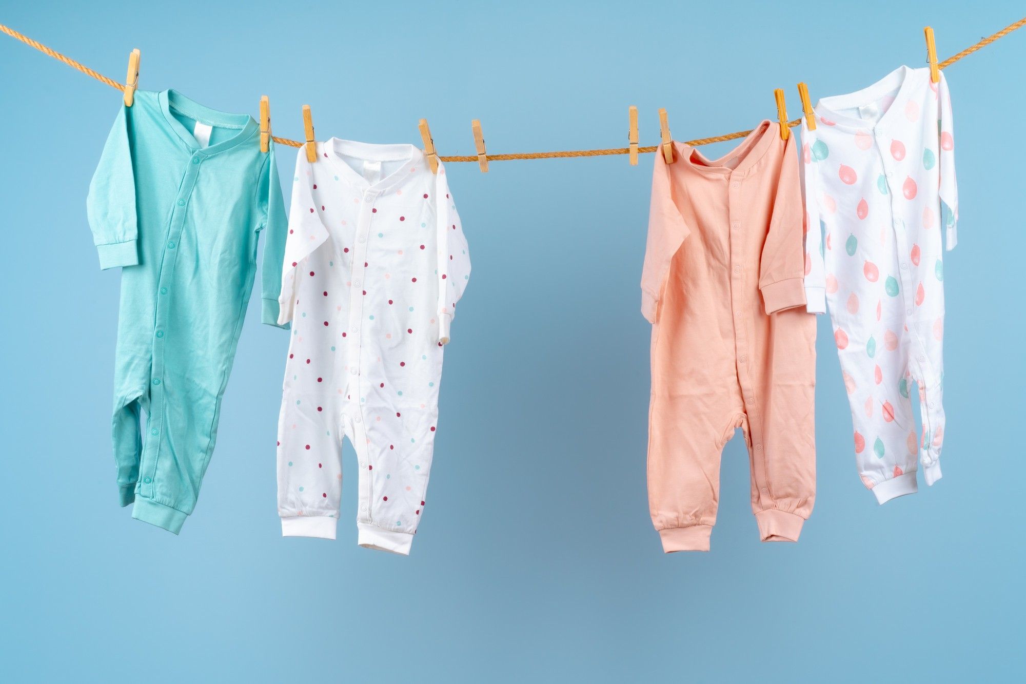 Pijamas de bebé colgados con pinzas en una cuerda.