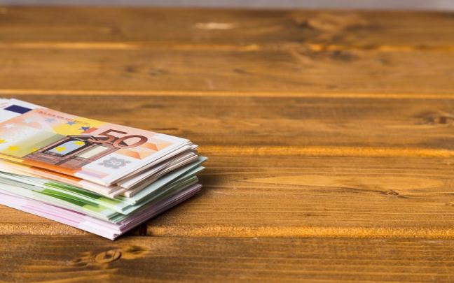 Taco de billetes de euro sobre una mesa de madera. Taco de billetes de euro sobre una mesa de madera.