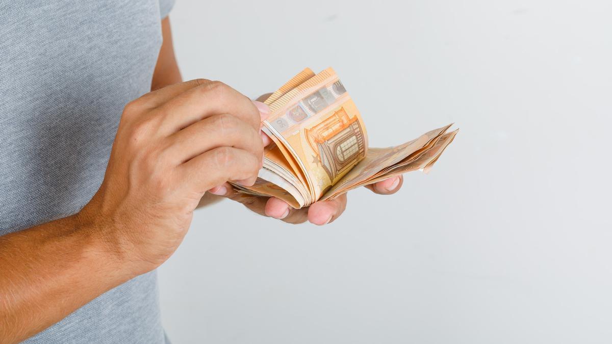 Una persona, con un fajo de billetes de 50 euros en las manos.