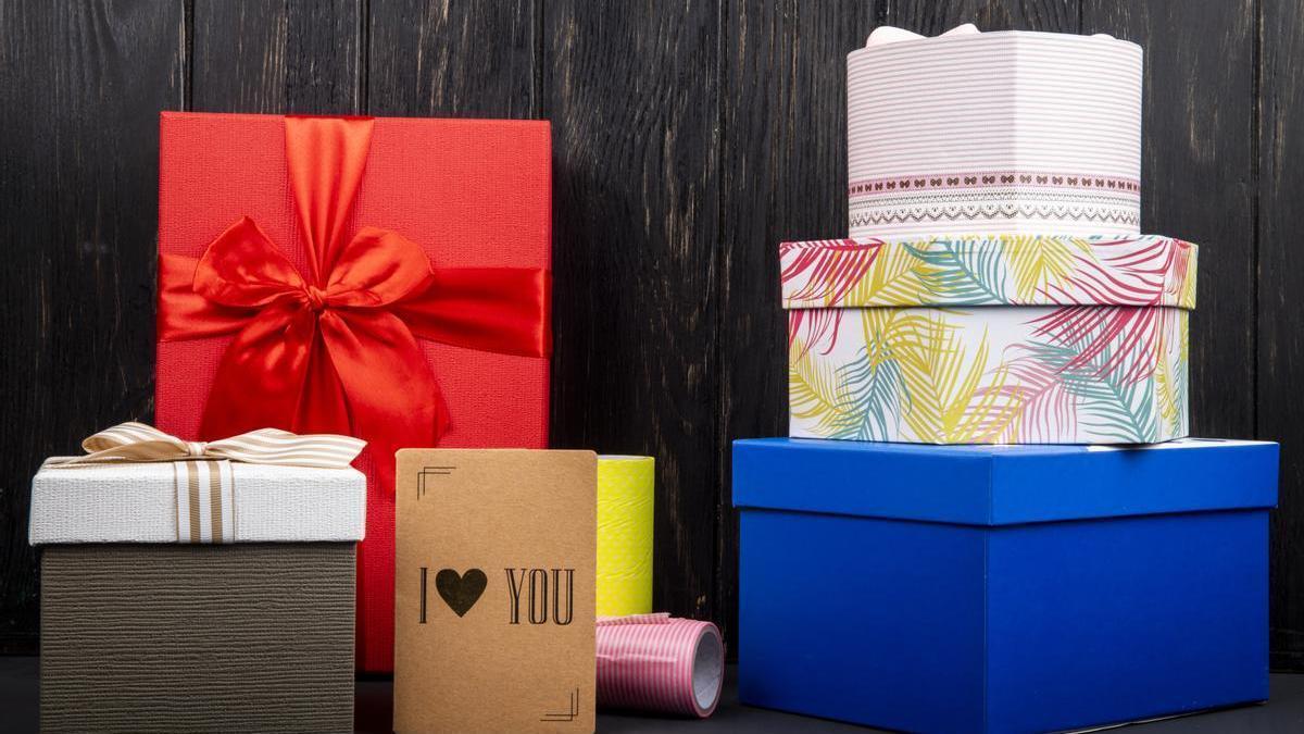 Cajas de regalo coloridas y una pequeña tarjeta de "te amo" en una mesa de madera oscura