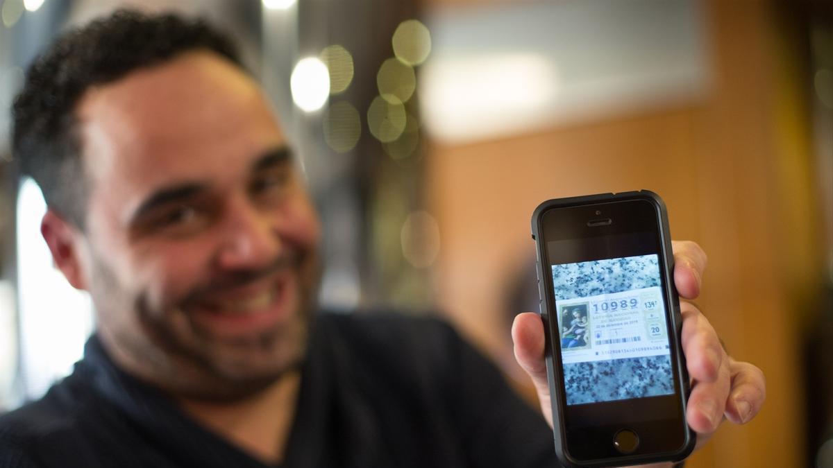 Uno de los agraciados por el Segundo Premio del Sorteo Extraordinario de Lotería de Navidad 2019 muestra una fotografía del décimo en su teléfono móvil