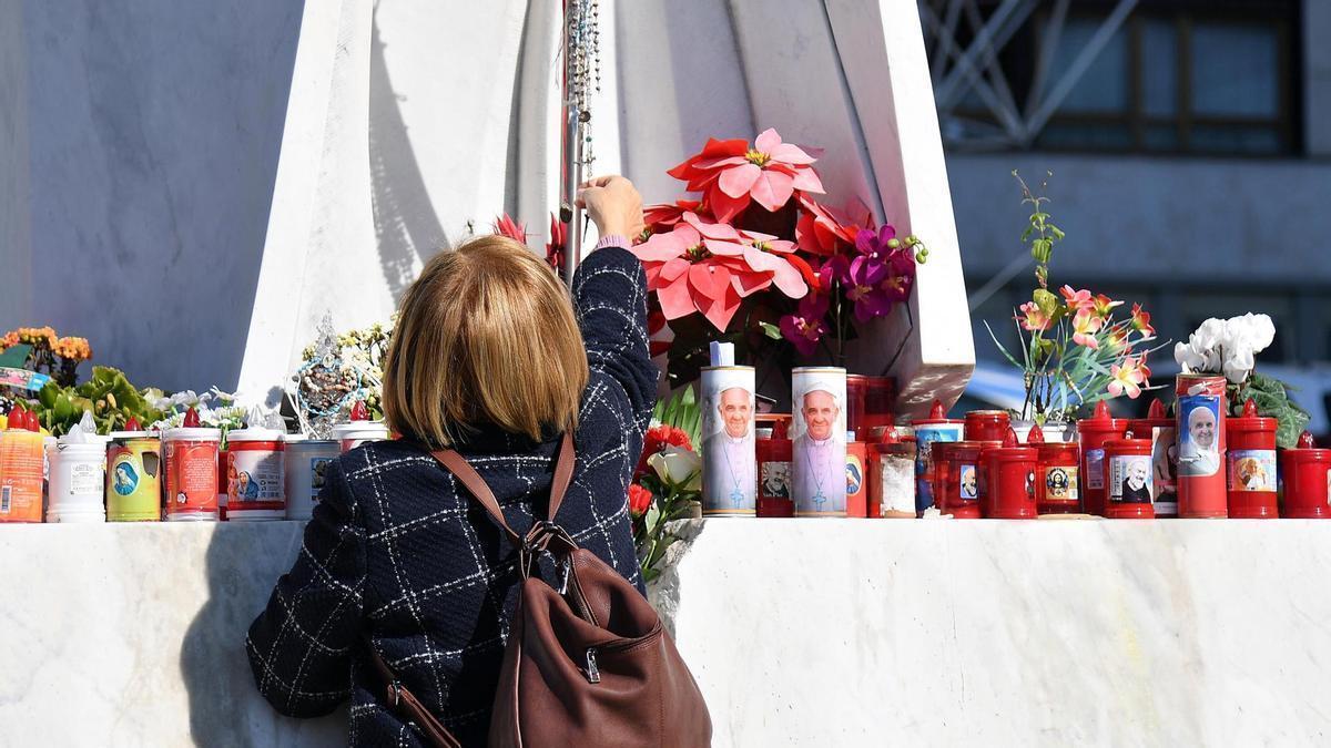 Una mujer cuelga un rosario en un altar improvisado en el exterior del hospital Gemelli de Roma.