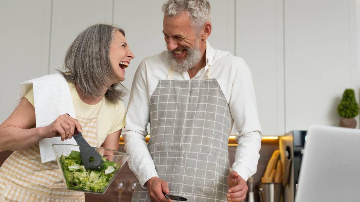Pareja preparan la cena felices en la cocina.