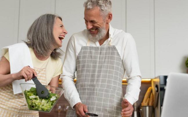 Pareja preparan la cena felices en la cocina.