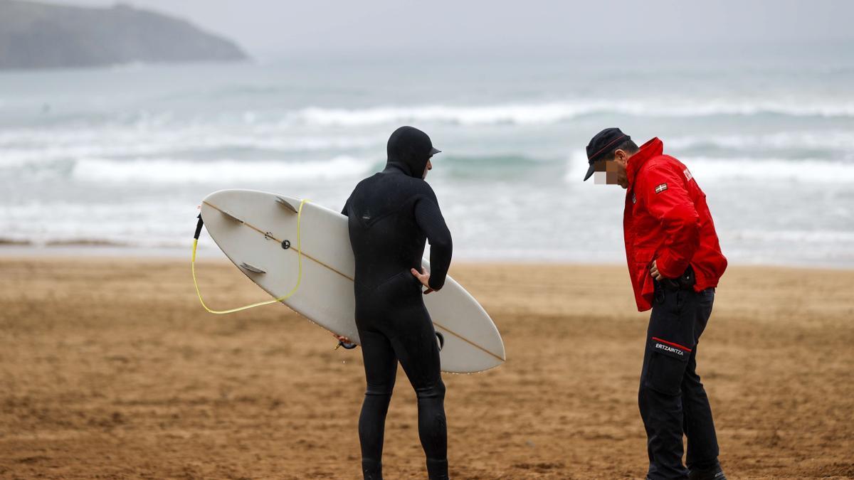 Un surfista y un ertzaina conversan en la playa de La Arena (Muskiz). Foto: Europa Press