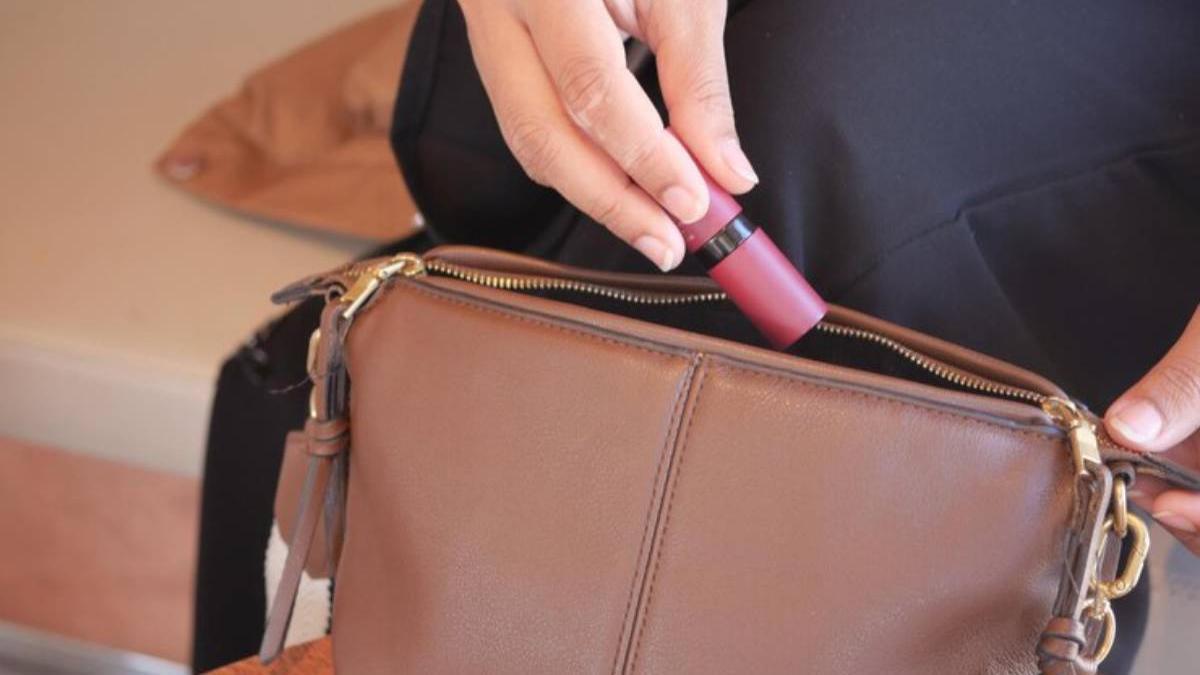 Chica guarda un pintalabios en su bolso.