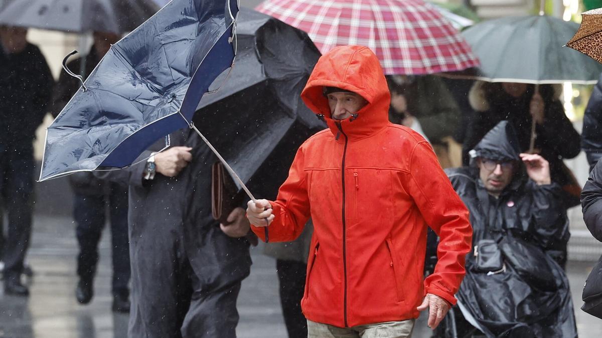 hombre trata de protegerse de la lluvia y el viento este jueves en Bilbao.