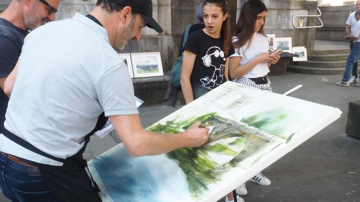 Un pintor trabaja en el remate del cuadro en el que participa en un concurso de pintura al aire libre.