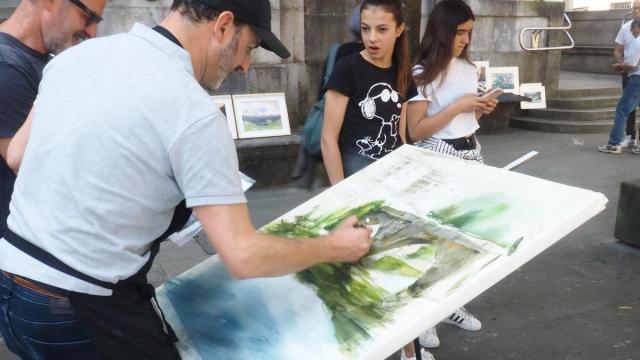 Un pintor trabaja en el remate del cuadro en el que participa en un concurso de pintura al aire libre.