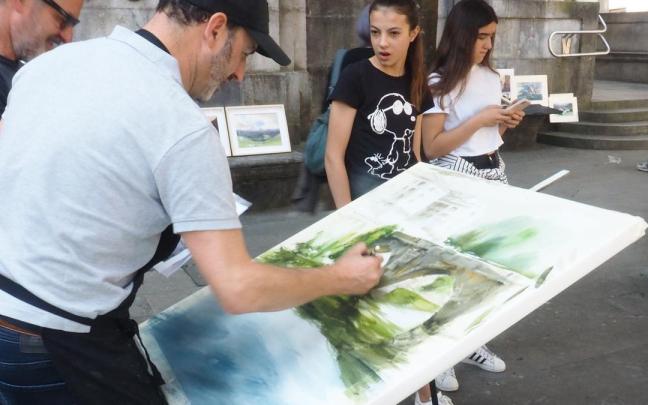Un pintor trabaja en el remate del cuadro en el que participa en un concurso de pintura al aire libre.