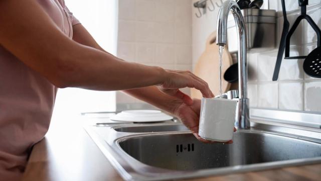 Una mujer lava una taza.