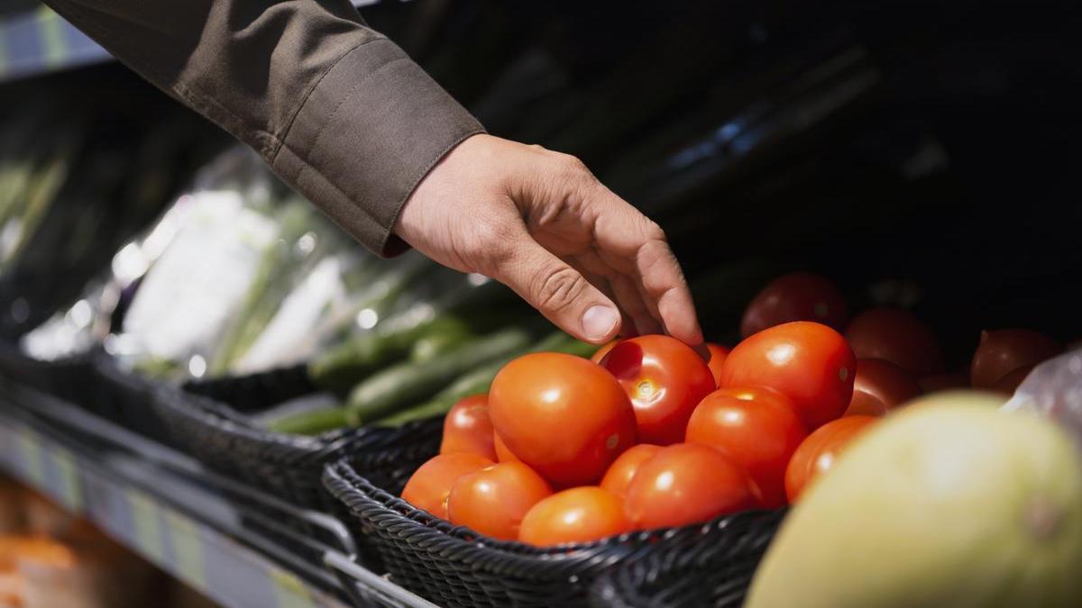 Chico selecciona los tomates que va a comprar en la frutería.