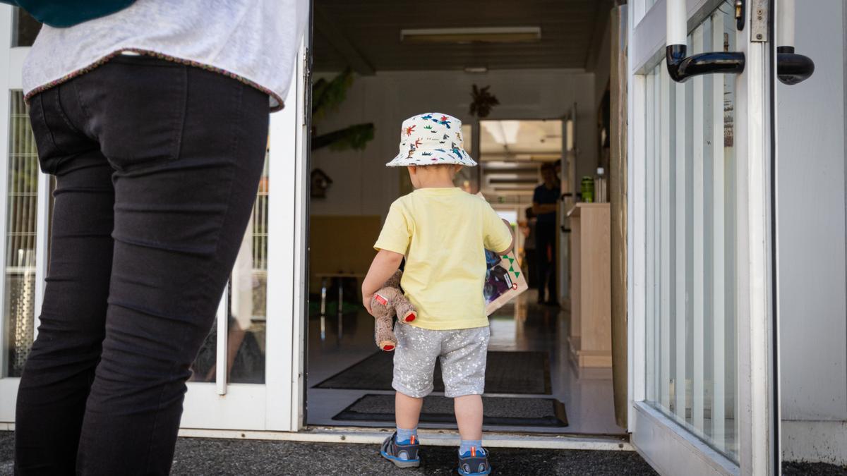 Un niño pequeño entra por la puerta hacia el interior de las instalaciones de una guardería