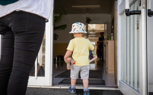 Un niño pequeño entra por la puerta hacia el interior de las instalaciones de una guardería