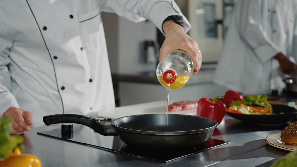 Un cocinero echa un chorro de aceite en la sartén