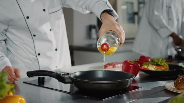 Un cocinero echa un chorro de aceite en la sartén