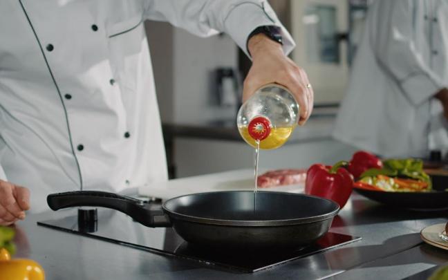 Un cocinero echa un chorro de aceite en la sartén