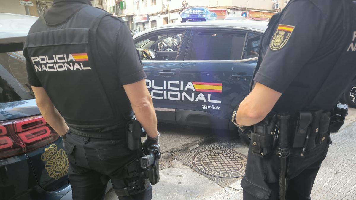Agentes de la Policía Nacional frente a un vehículo policial.