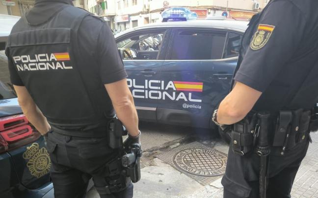 Agentes de la Policía Nacional frente a un vehículo policial.