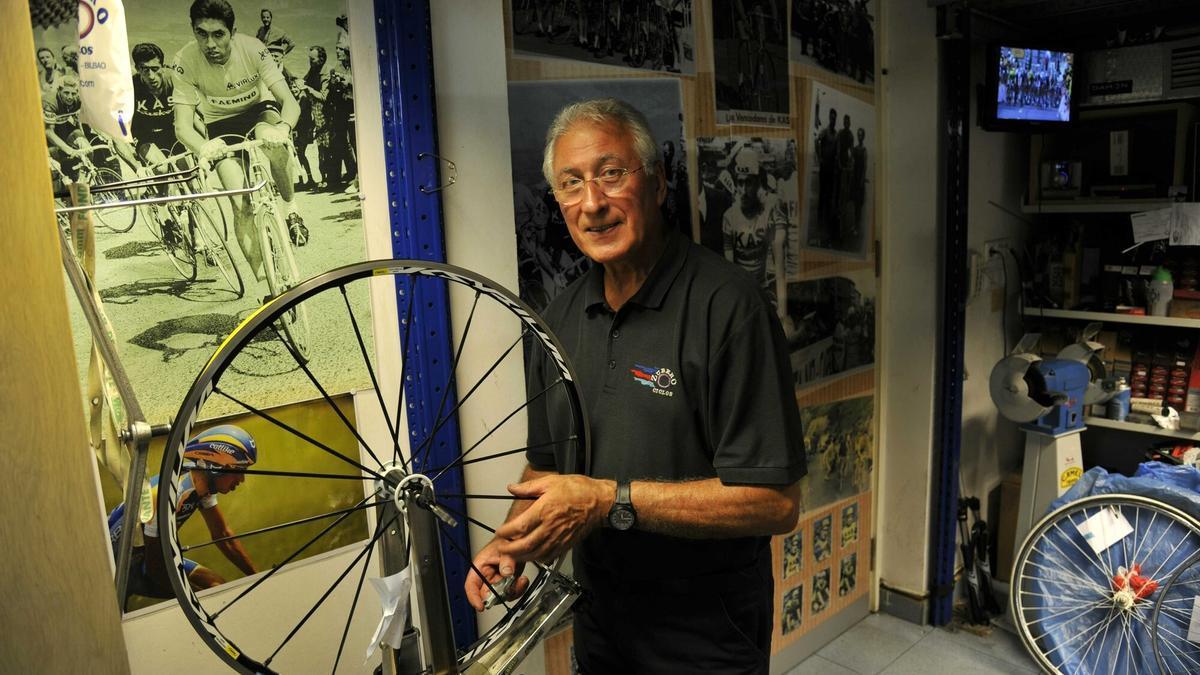 Luis Zubero posa en su negocio de bicicletas delante de una foto en la que persigue a Merckx.