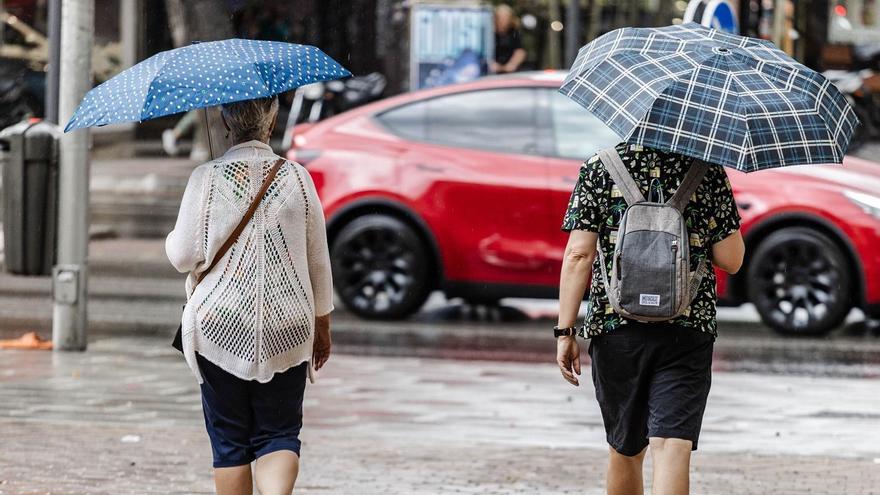 Dos personas caminan bajo la lluvia.