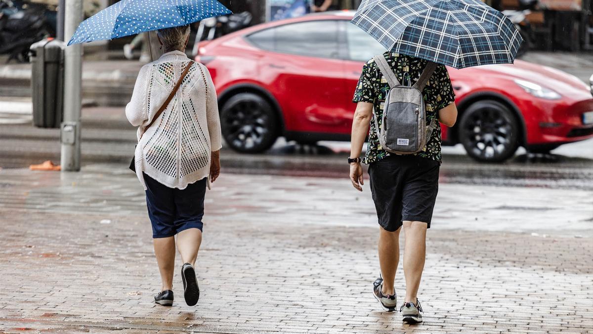 Dos personas caminan bajo la lluvia.