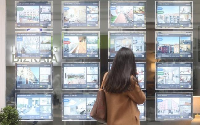 Una mujer mira los precios de los pisos en una inmobiliaria de Bilbao.