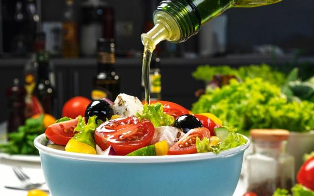 Chorro de aceite de oliva vertido sobre una ensalada.