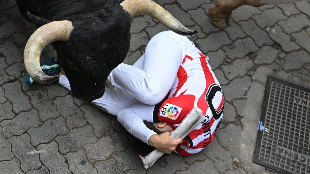 Un toro pasa por encima de un mozo en el tercer encierro de Sanfermines.