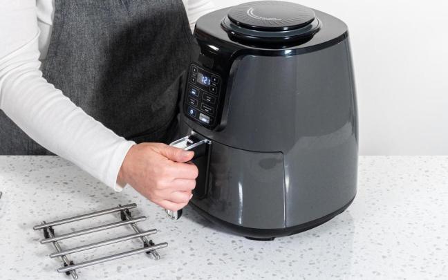 Una cocinera prepara la freidora de aire.