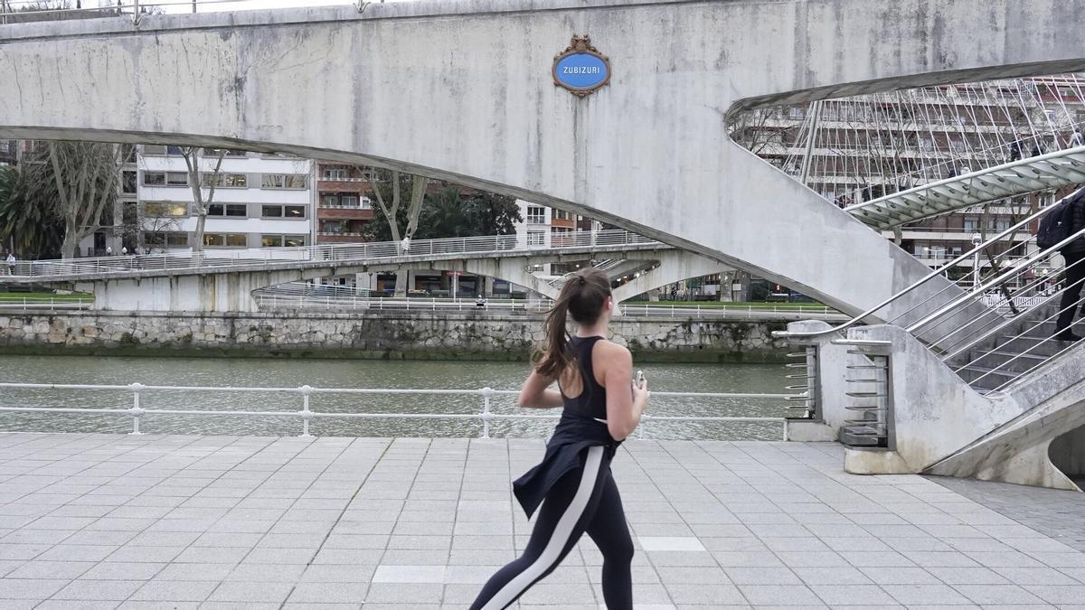 Una joven corre junto al puente Zubizuri de Bilbao.
