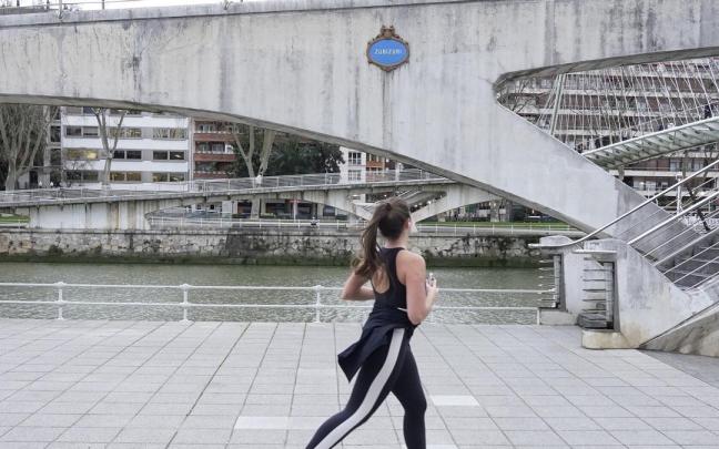 Una joven corre junto al puente Zubizuri de Bilbao.