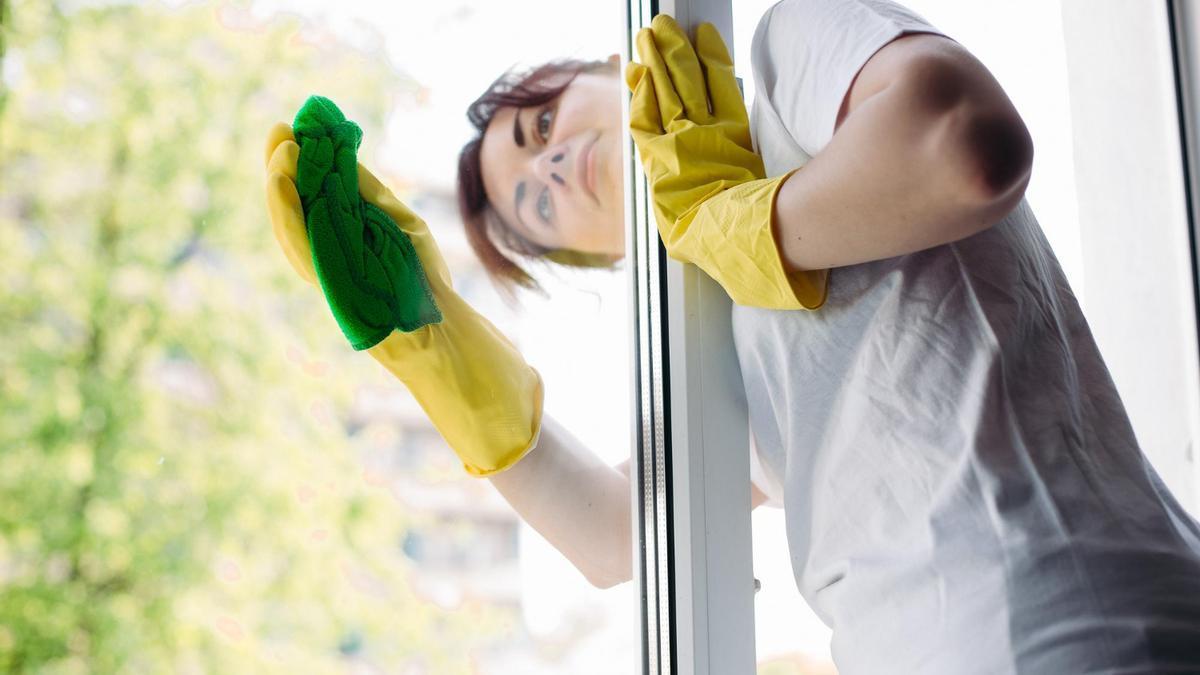 Una mujer limpia los cristales de su casa