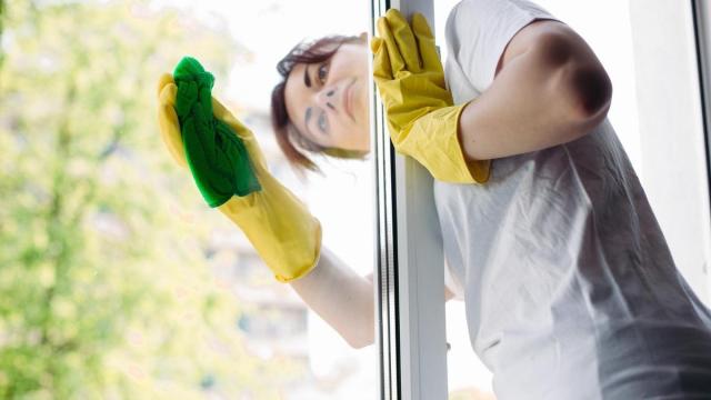 Una mujer limpia los cristales de su casa