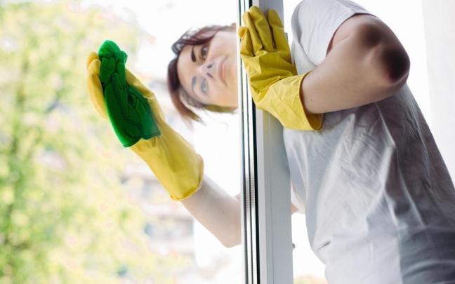 Una mujer limpia los cristales de su casa