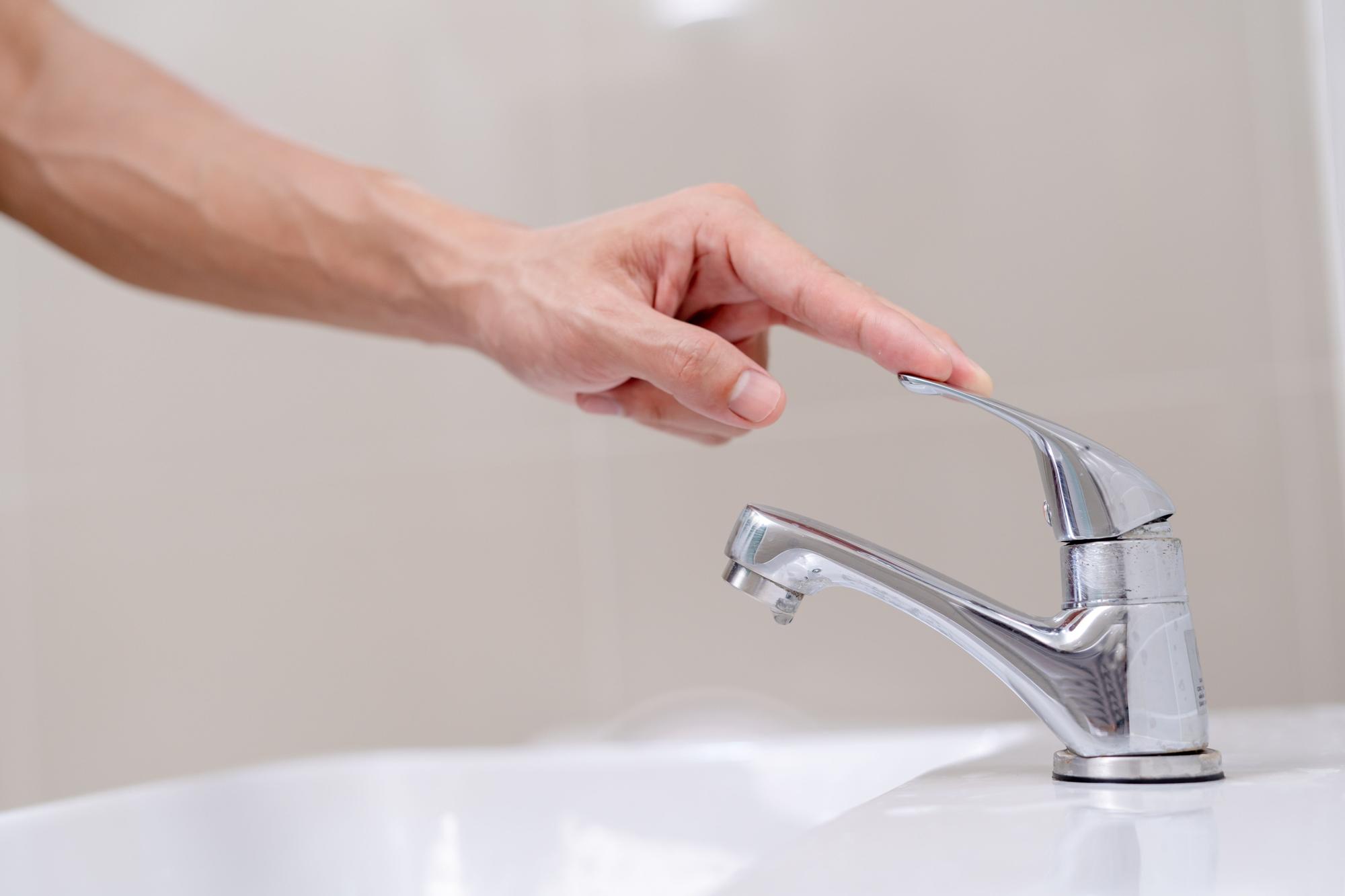 Mujer comprueba que uno de los grifos del baño esté bien cerrado.