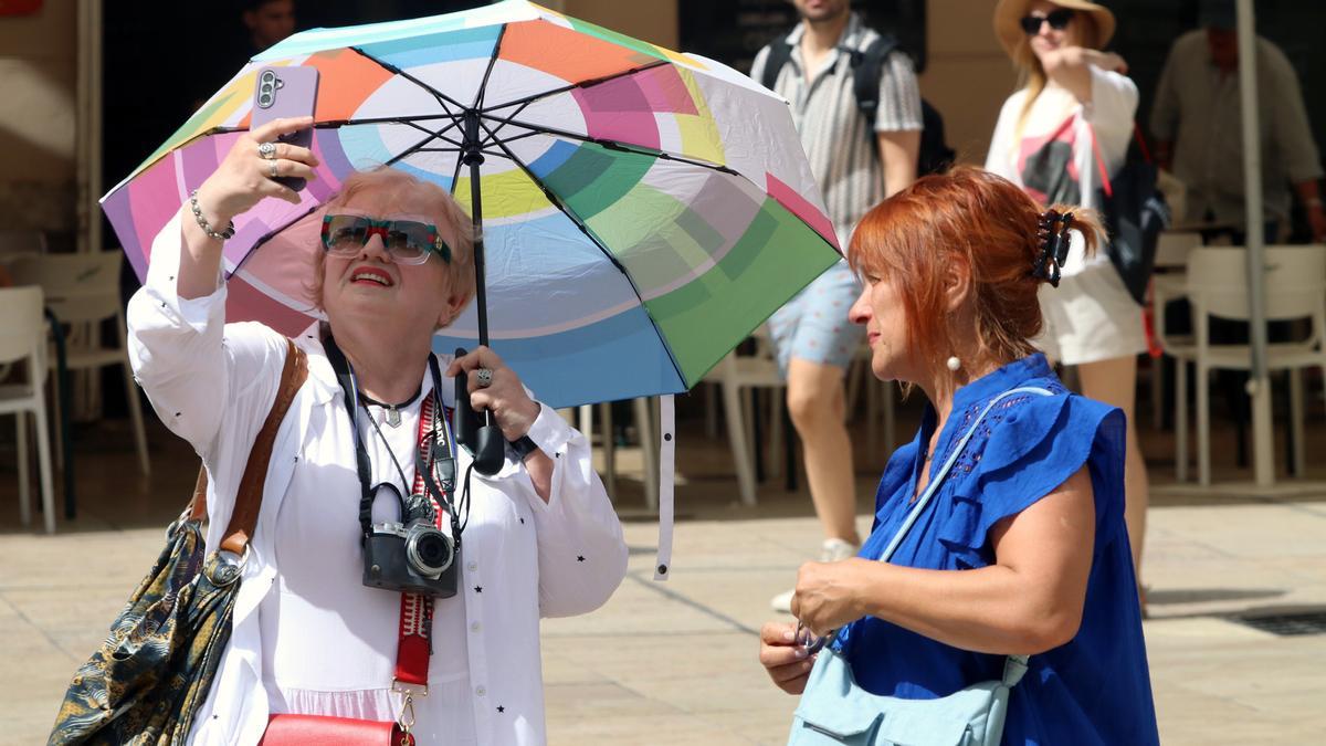 Dos mujeres se protegen del sol con una sombrilla en Málaga.