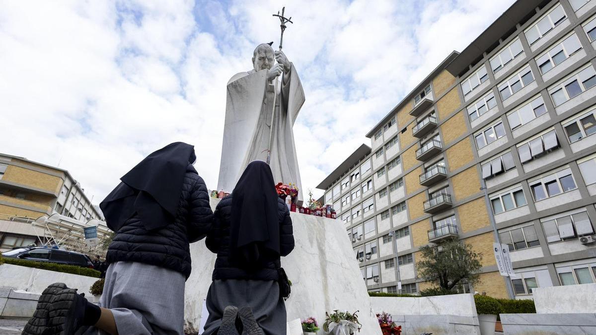 Dos monjas rezan ante la estatua de Juan Pablo II en el Hospital Gemelli.