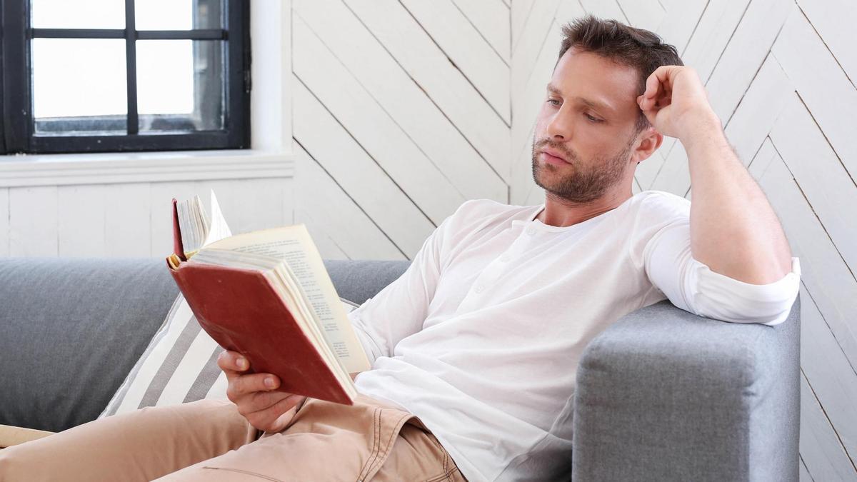 Un hombre disfruta de un rato de lectura en el salón de su casa.