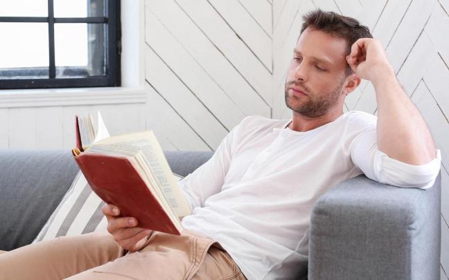 Un hombre disfruta de un rato de lectura en el salón de su casa. Un hombre disfruta de un rato de lectura en el salón de su casa.