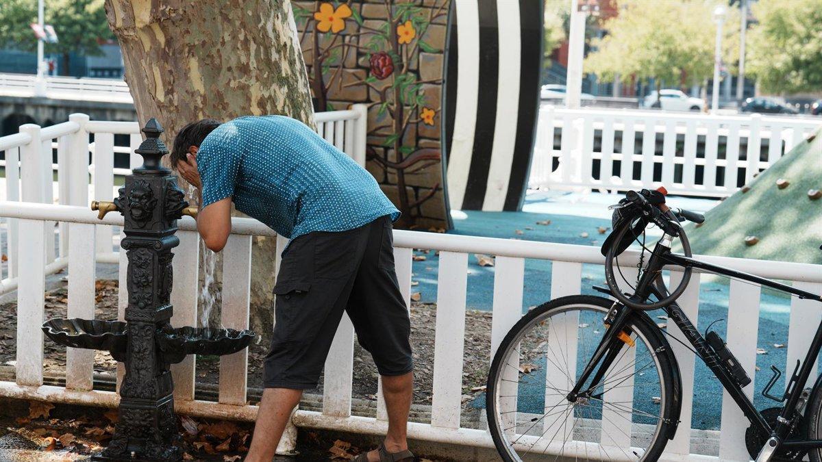 Un hombre se moja la cara con el agua de una fuente durante una ola de calor en Bilbao