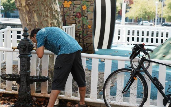 Un hombre se moja la cara con el agua de una fuente durante una ola de calor en Bilbao
