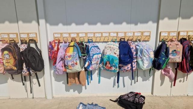 Un perchero con mochilas en un centro educativo.