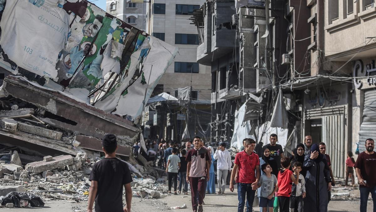 Ciudadanos palestinos caminan junto a edificios destruidos por los bombardeos israelíes.