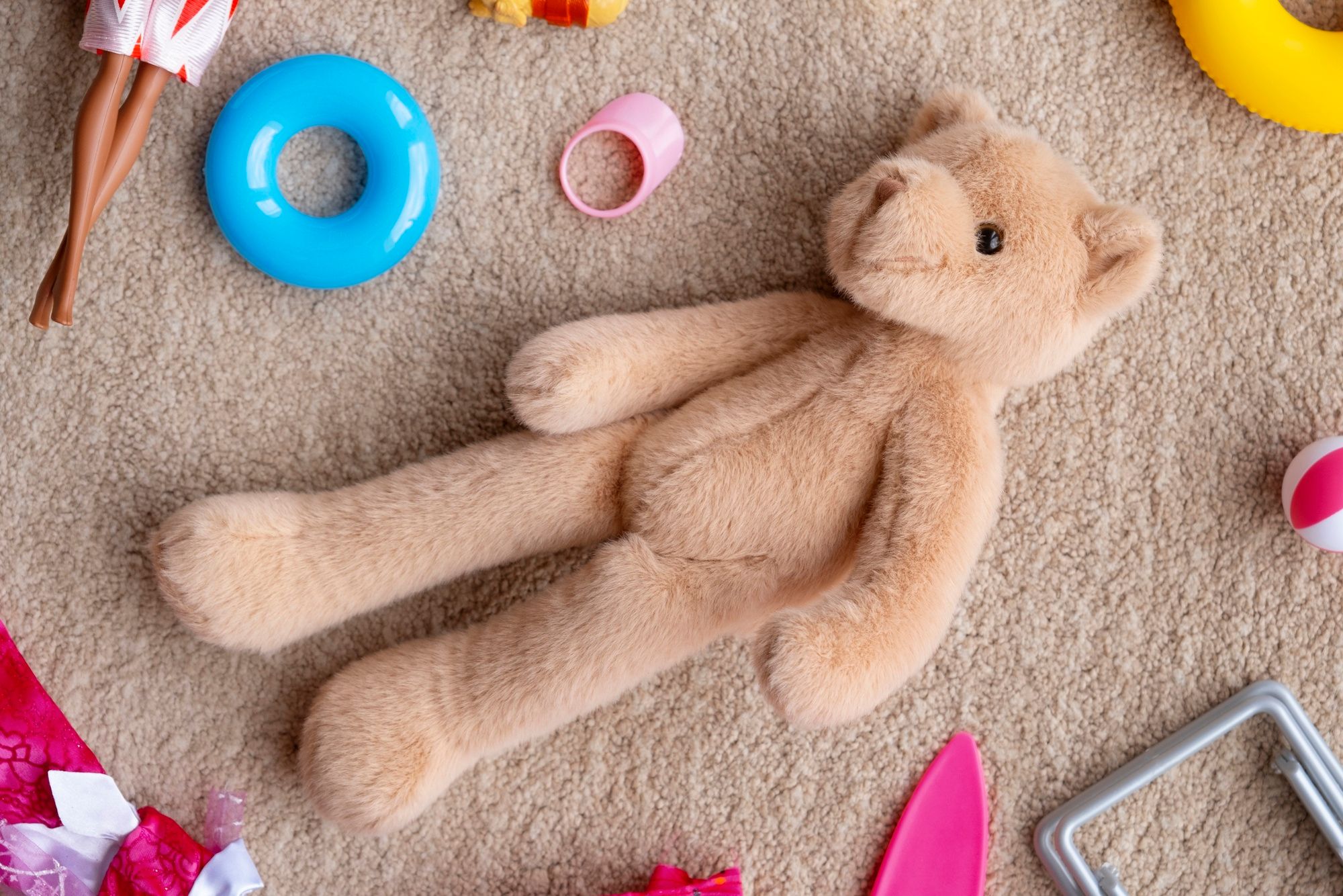 Un peluche y otros juguetes tirados sobre la alfombra del dormitorio.