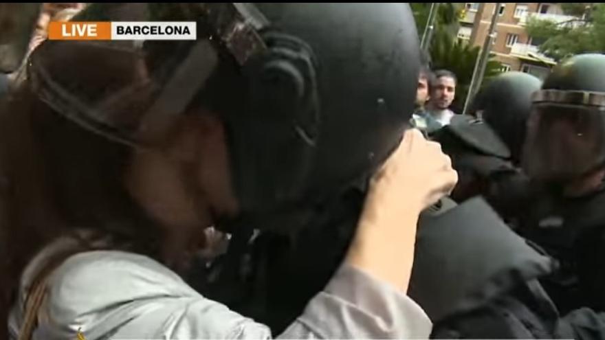 Momento en el que la mujer besa al agente antidisturbios.